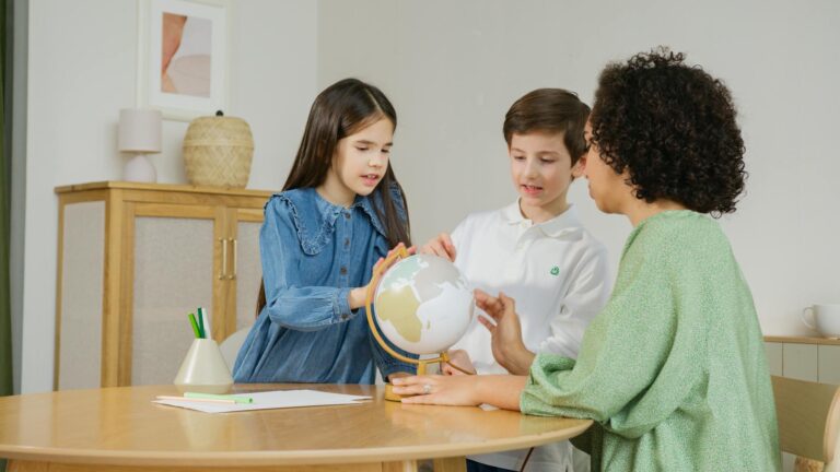 Children and teacher exploring globe for geography lesson indoors.