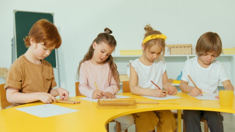 Group of children attentively writing and drawing during classroom learning activities.