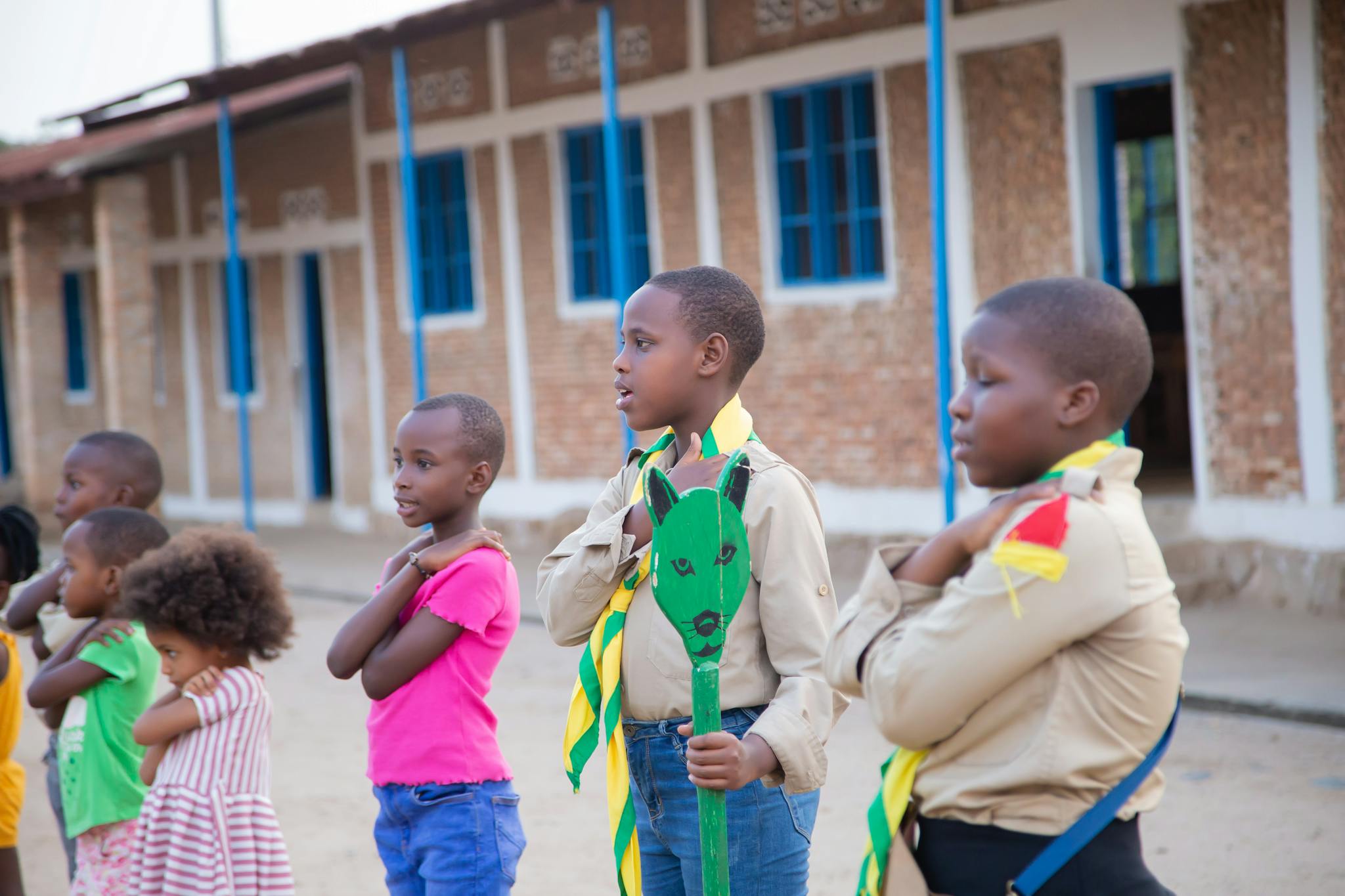 Group of children in school uniforms engaging in an outdoor activity on a sunny day.
