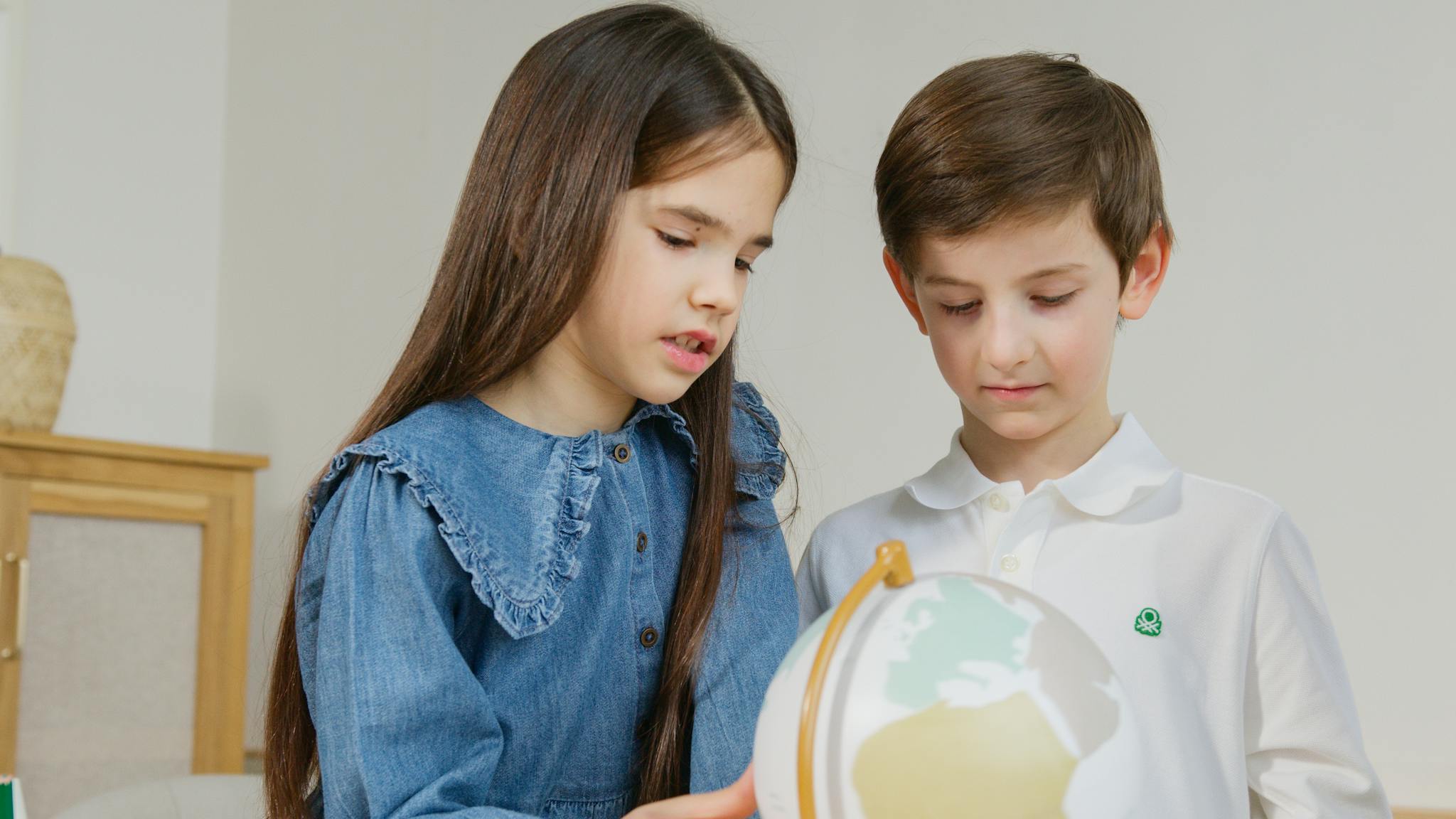 Two children studying geography with a globe, fostering curiosity and learning.